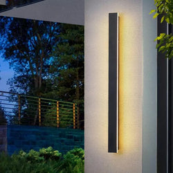 Outdoor aluminum long LED wall sconce mounted on an exterior wall, illuminating the surrounding area 