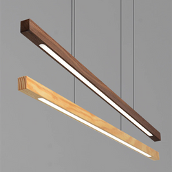 Two wooden linear pendant lights, one made of pine wood with a light tan hue, and the other made of black walnut wood showcasing a rich dark brown shade