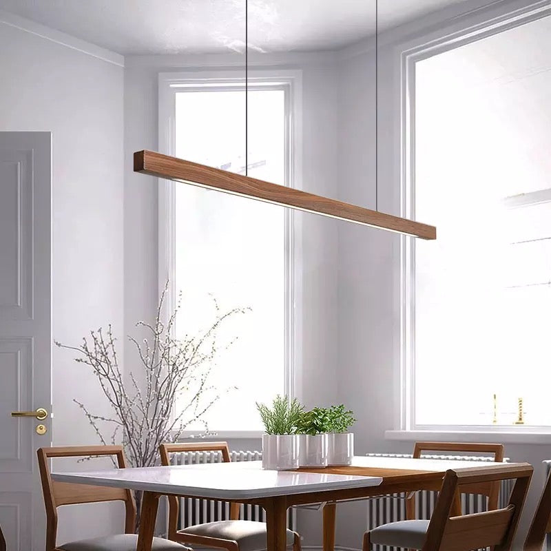 Walnut wood linear pendant light hanging over table