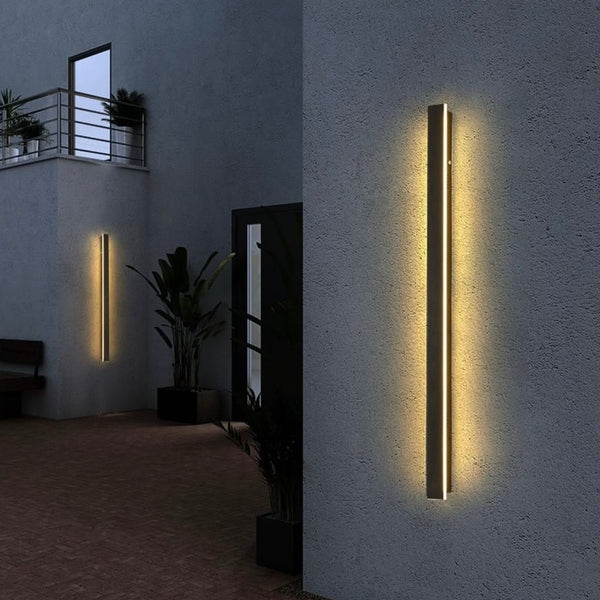 Outdoor aluminum long LED wall sconce mounted on an exterior wall, illuminating the surrounding area